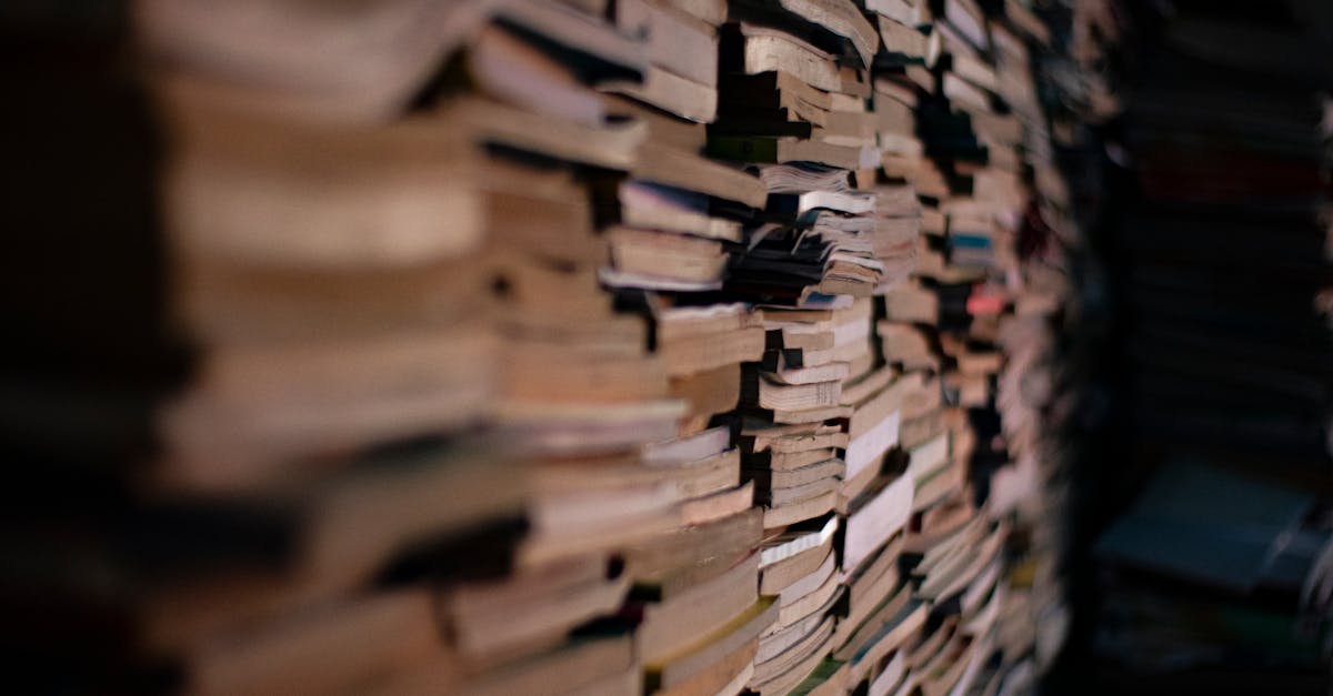 A dense stack of books creating a sense of depth and knowledge in a dimly lit room.