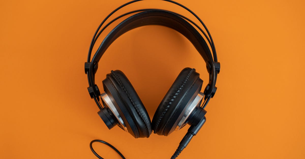 Top view of modern black headphones elegantly posed on a vibrant orange surface.
