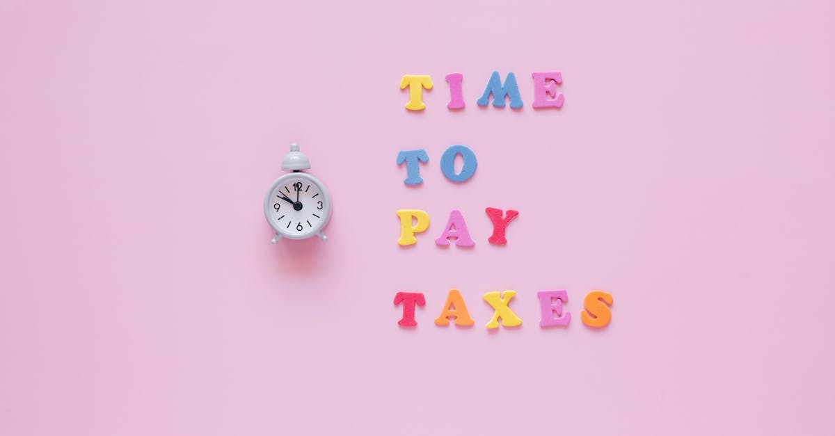 Colorful letters spell 'Time to Pay Taxes' next to a clock on a pink surface.